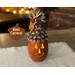 This is a carved pumpkin gourd named Carsen. He has a happy face carved into the shell and his top is decorated with real pine cone scales.